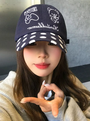 Navy baseball cap with white polka dot brim and embroidered bear graphic