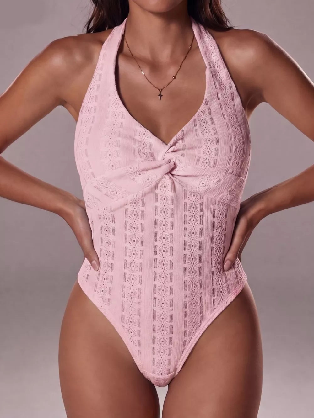 Pink lace halter bodysuit with twisted front and intricate pattern.