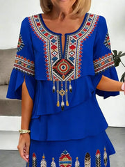 Blue boho tiered dress with embroidered neckline, bell sleeves, and feather details.