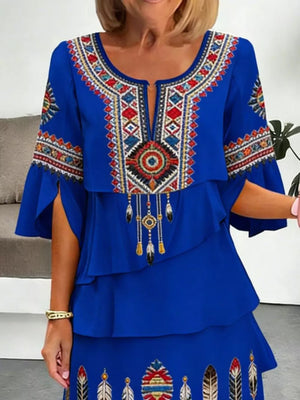 Blue boho tiered dress with embroidered neckline, bell sleeves, and feather details.