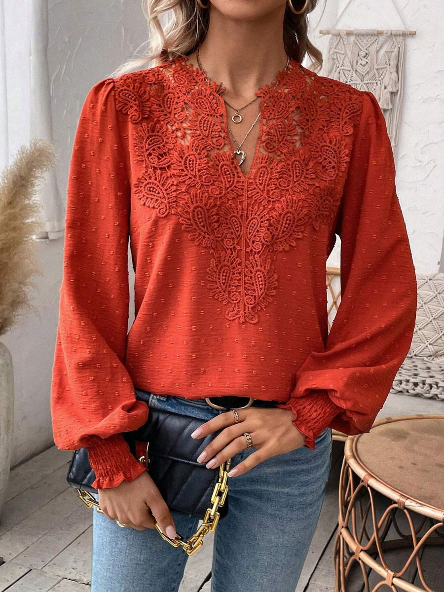 Orange-red embroidered yoke blouse with puff sleeves and textured fabric.
