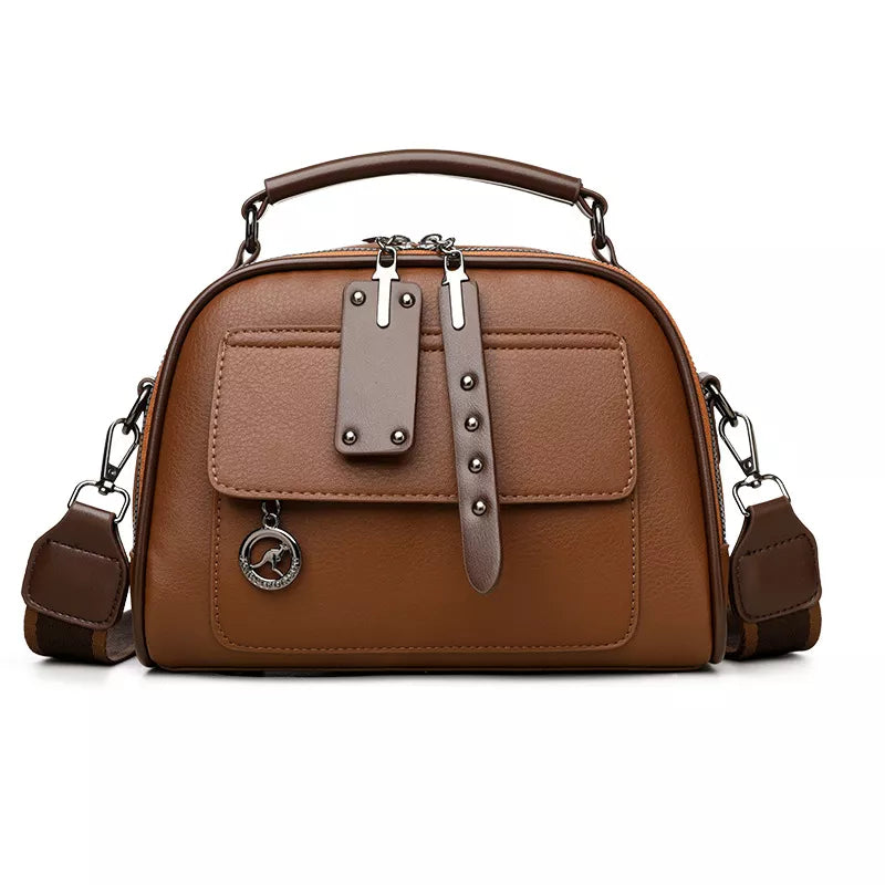 Brown structured crossbody bag with adjustable strap and metal charm detail.