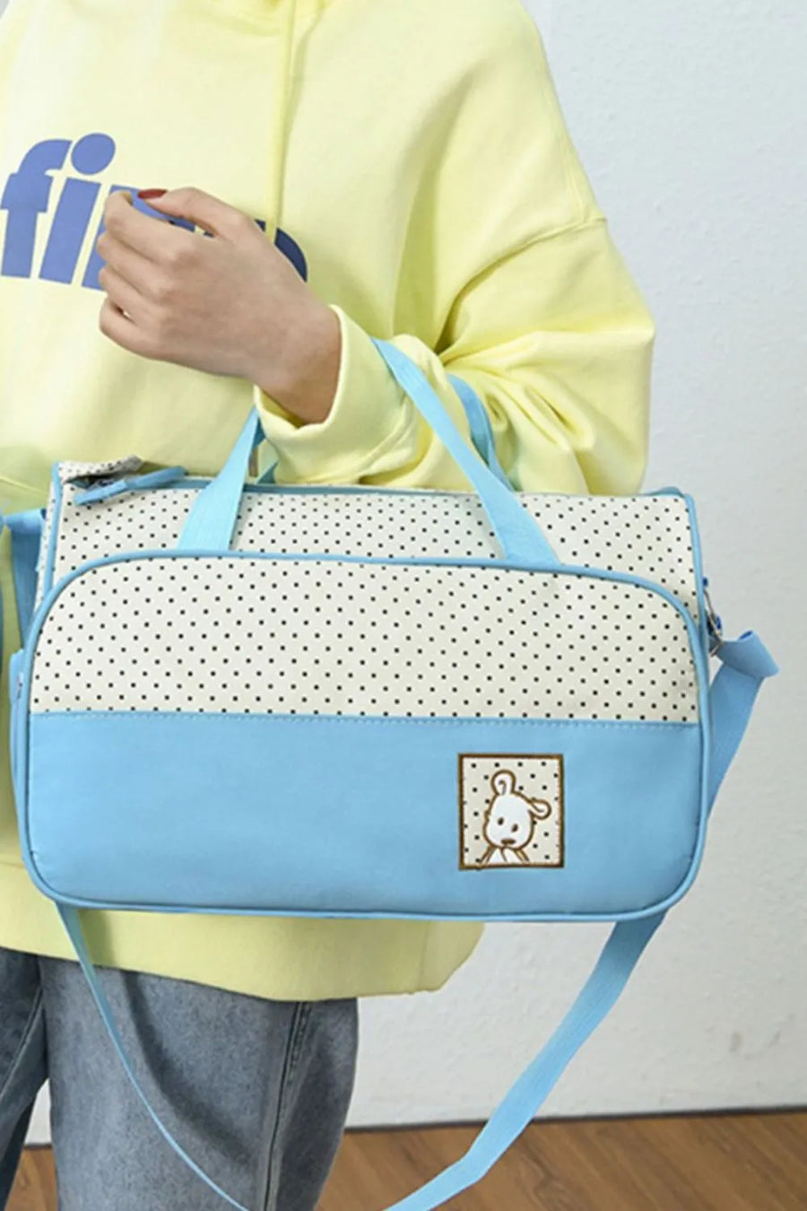 Pastel blue and white polka dot diaper bag with a cute bear applique.
