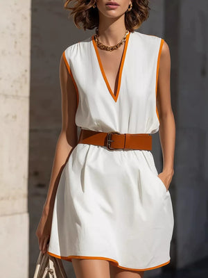 White sleeveless mini dress with orange trim, V-neck, and brown belt.