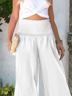 White smocked waist wide-leg trousers with a textured fabric and flowy cut.