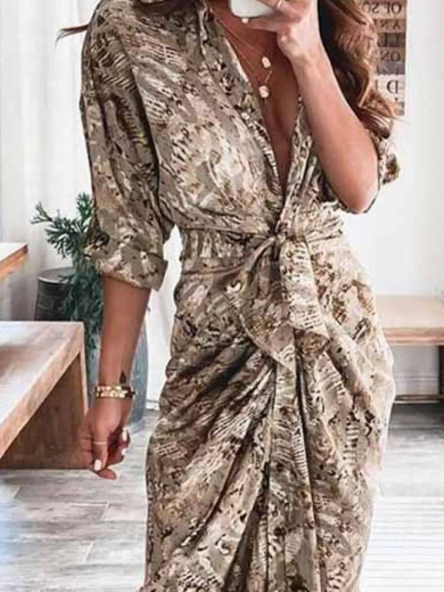 Elegant tie-waist midi dress in a brown abstract print with a deep V-neck and ruched skirt.