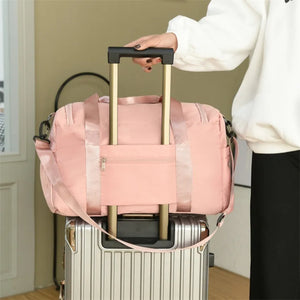 Dusty Pink duffel bag with utility pockets and adjustable strap, resting on a suitcase.
