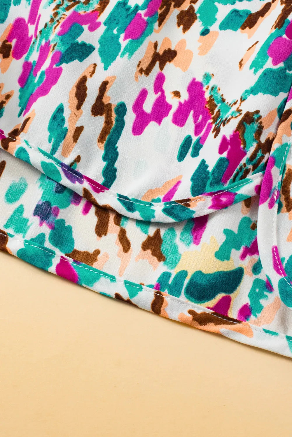 White running shorts with a colorful abstract brushstroke print and white stitching detail.