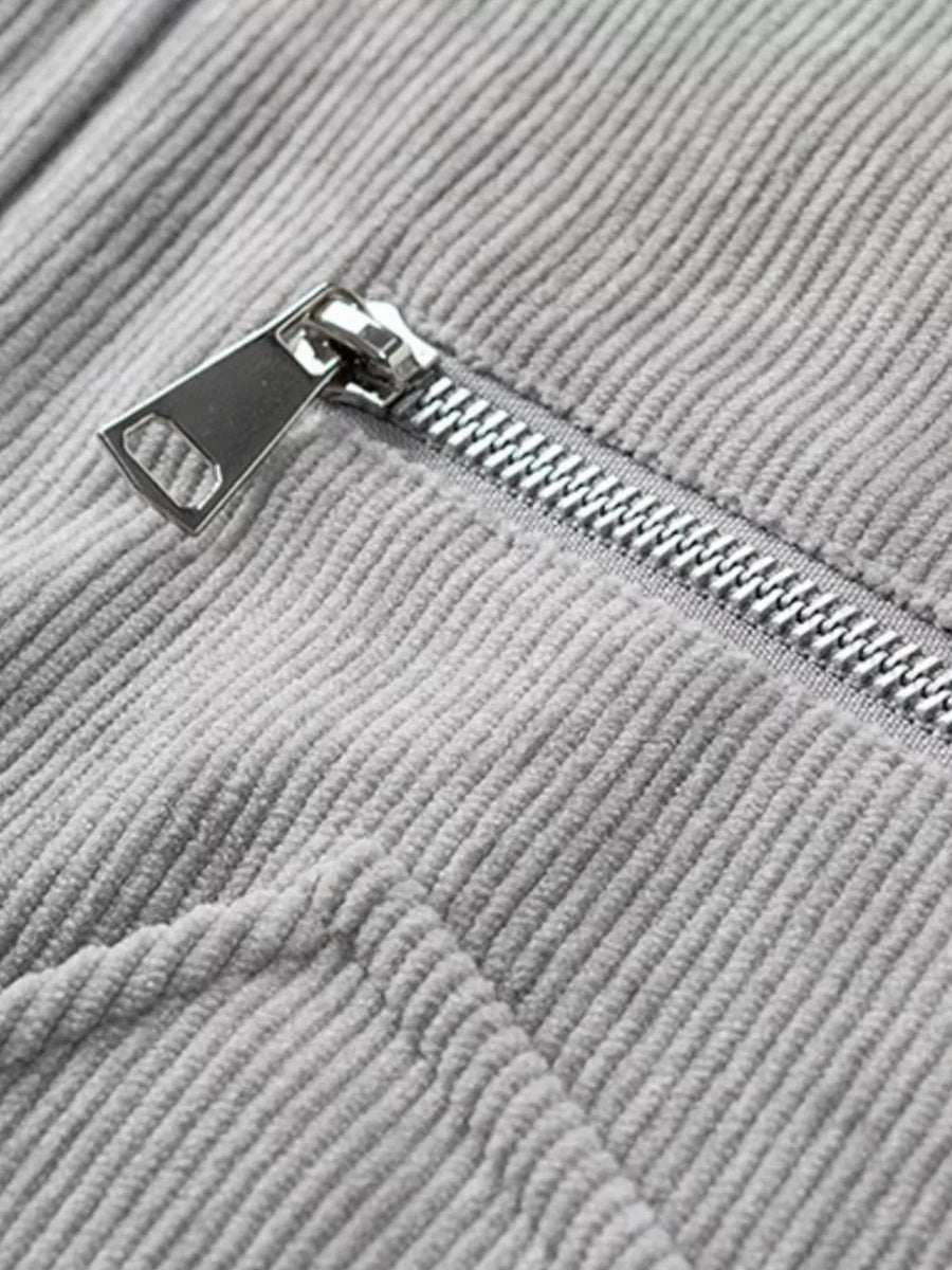 Grey corduroy trucker jacket detail with silver zipper and textured fabric.