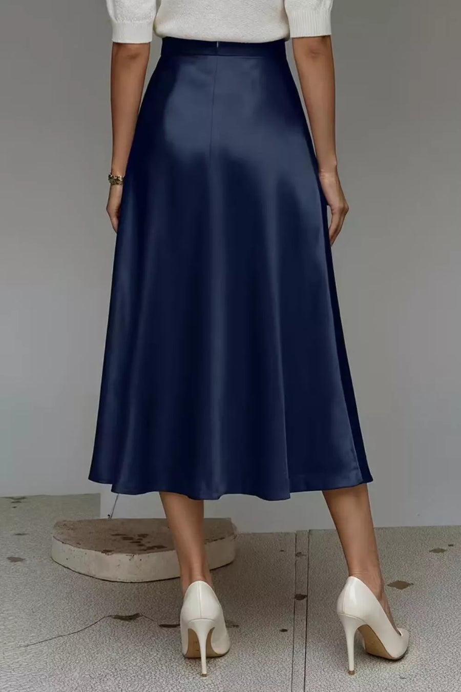 Navy A-line midi skirt with a lustrous finish and hidden pockets, shown from the back.