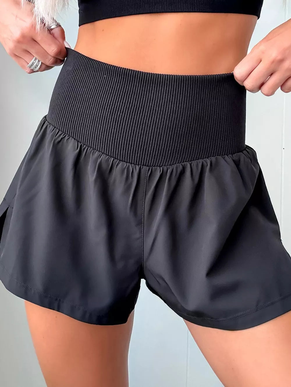 Black athletic shorts with a high-rise ribbed waistband and a relaxed fit.