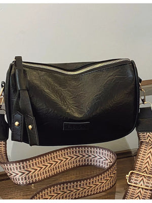Black crossbody bag with gold zipper and patterned strap