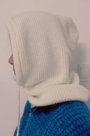 White knit balaclava with drawstring detail, worn with a blue sweater.