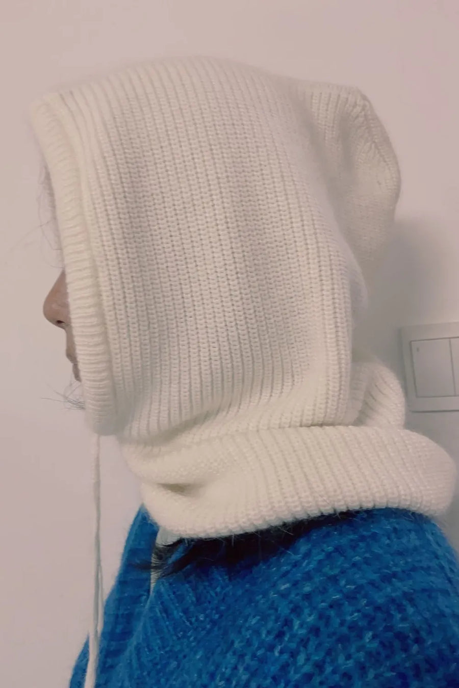 White knit balaclava with drawstring detail, worn with a blue sweater.