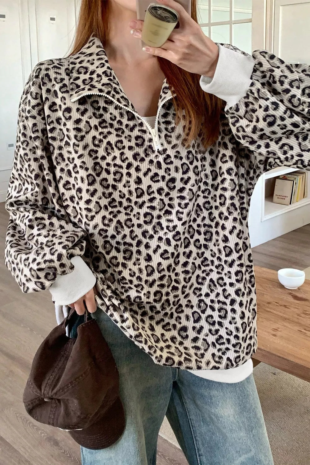 Leopard print quarter-zip sweatshirt with ribbed texture and white cuffs.