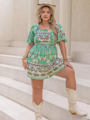 Plus-size green floral romper with square neck, cinched waist, and short sleeves.
