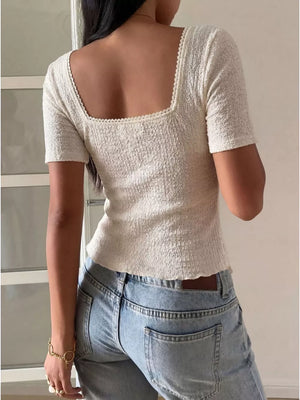 White textured square neck top with lace trim and short sleeves.