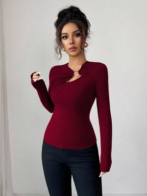 Burgundy long-sleeve tee with asymmetrical cutout and gold ring detail at neckline