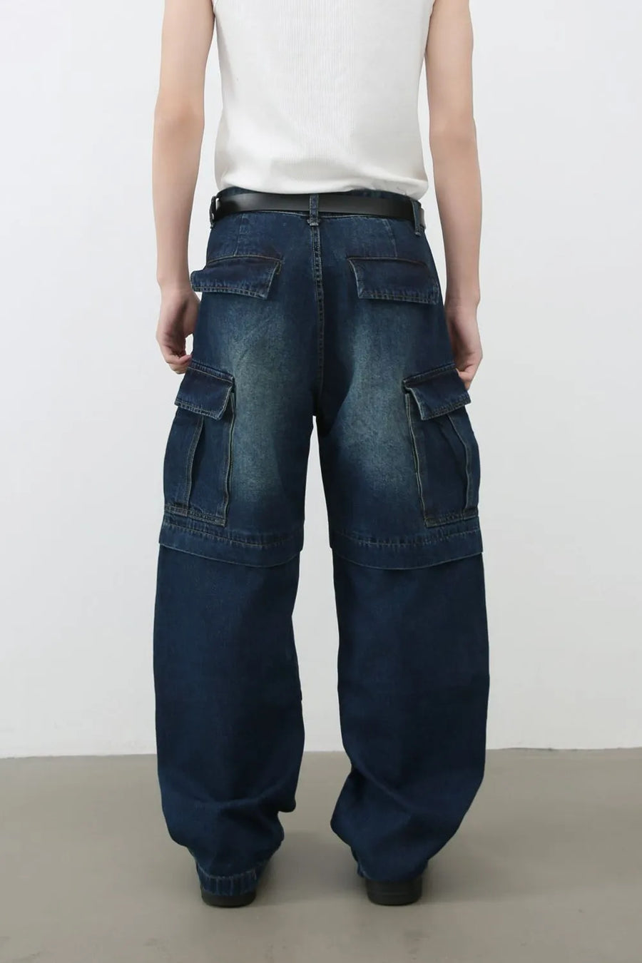 Dark denim cargo pants with layered pockets and a relaxed fit.