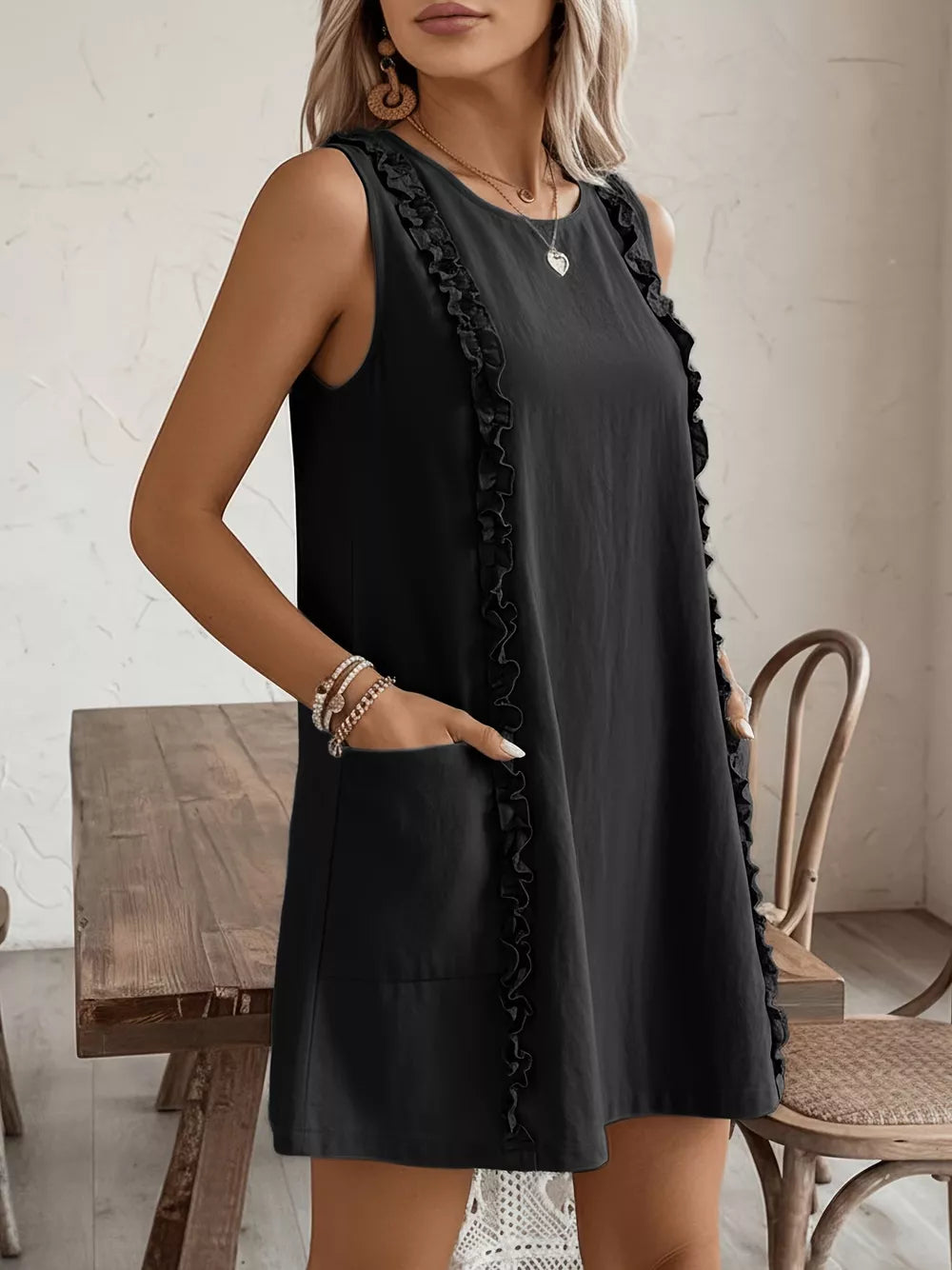 Black sleeveless dress with frill details and pockets.
