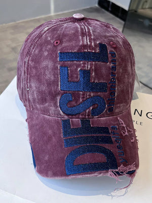 Distressed wine red baseball cap with blue embroidered lettering and frayed brim.