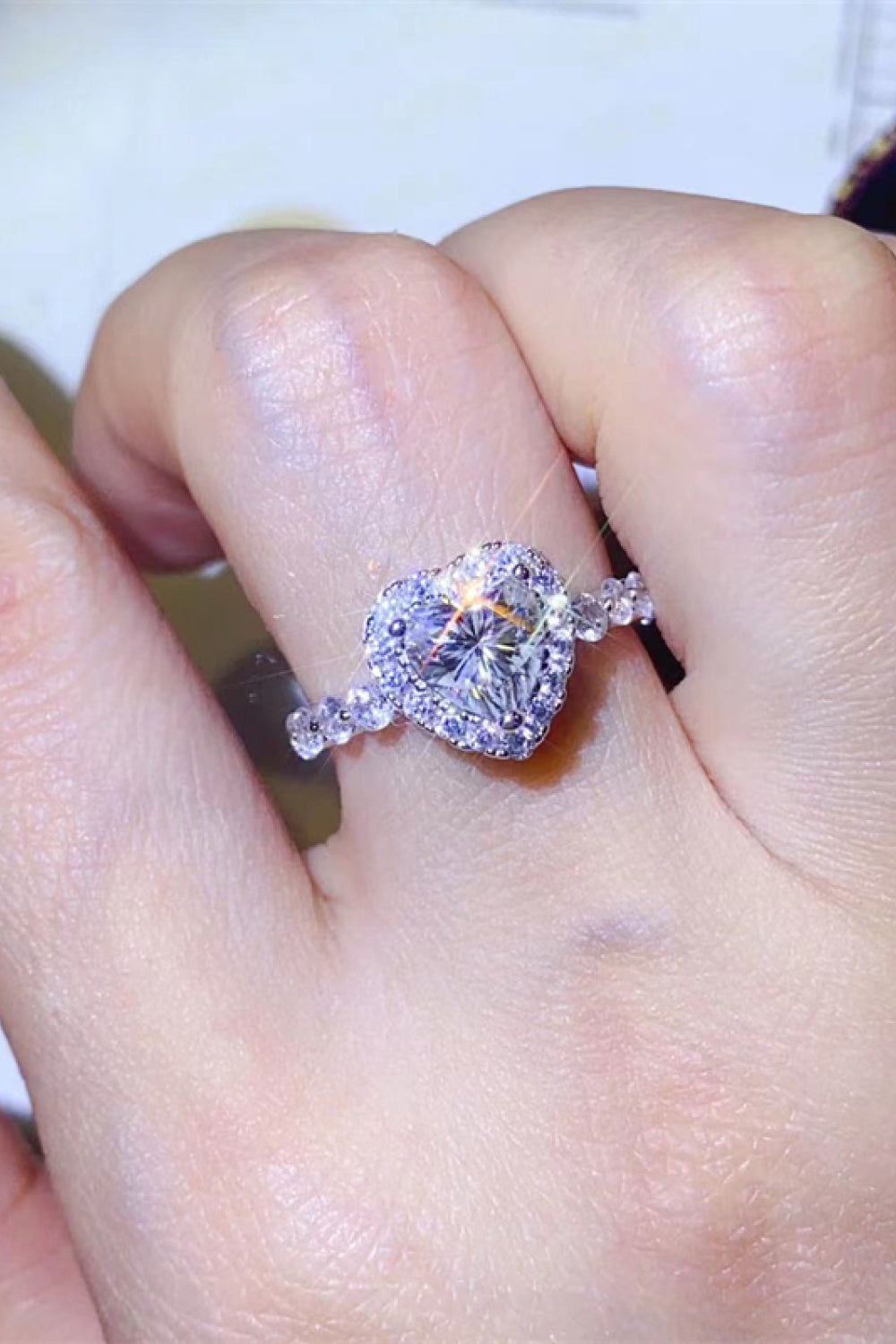 White moissanite halo engagement ring with heart-shaped center stone and diamond band.