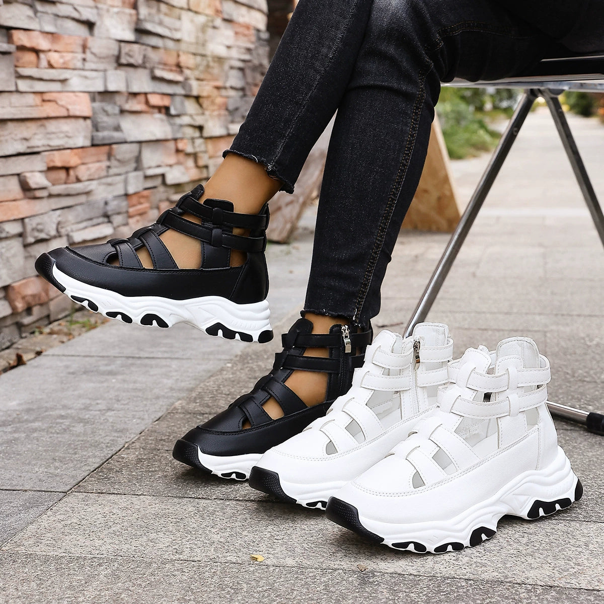 Chunky cutout platform sneakers in black and white with ankle straps and zipper detail.