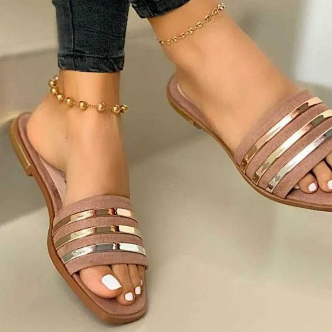 Beige open-toe flat sandals with metallic stripe detail and gold anklet