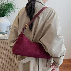 Chic suede crescent shoulder bag in red with adjustable strap.