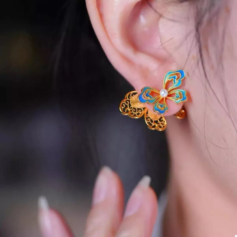 Gold butterfly stud earrings with blue enamel and pearl detail.