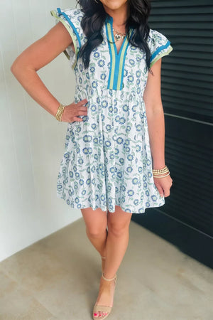 Floral cap sleeve dress with notched neckline and blue floral print on white cotton blend.