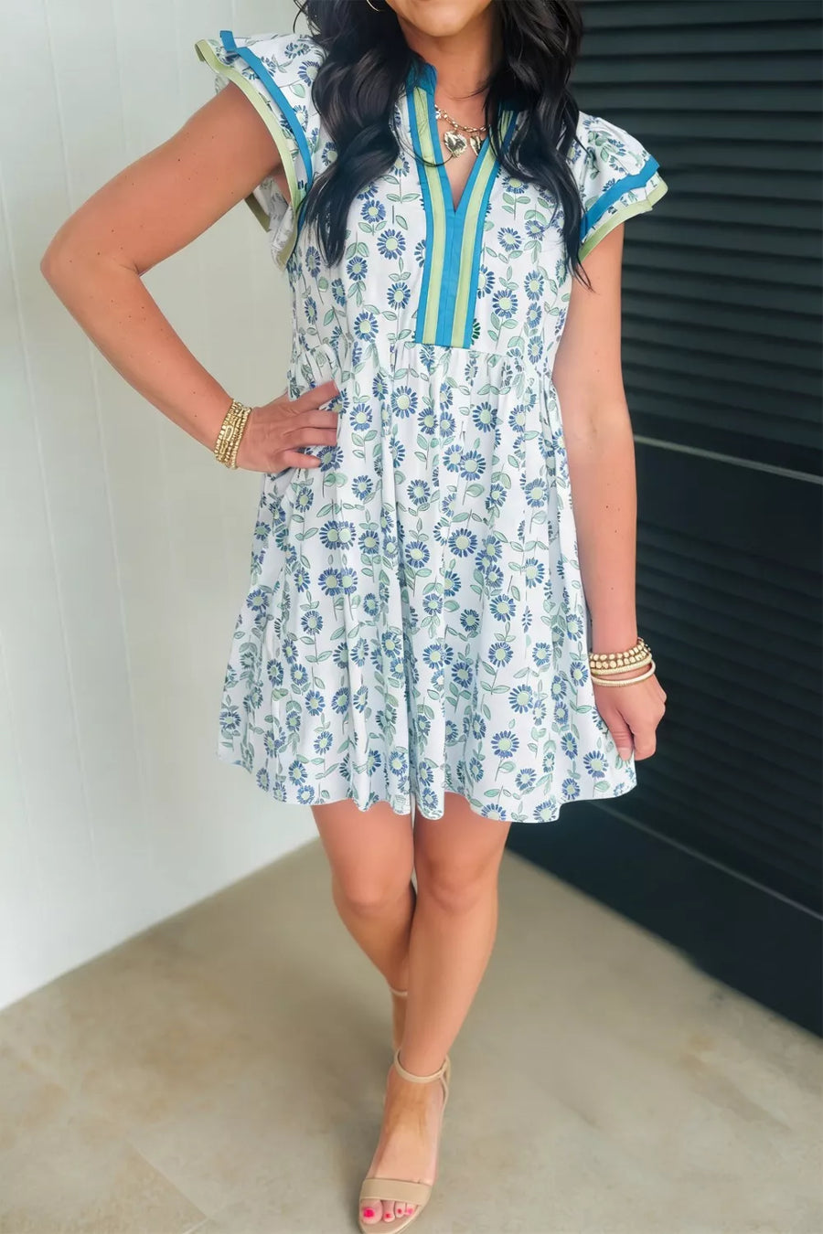 Floral cap sleeve dress with notched neckline and blue floral print on white cotton blend.