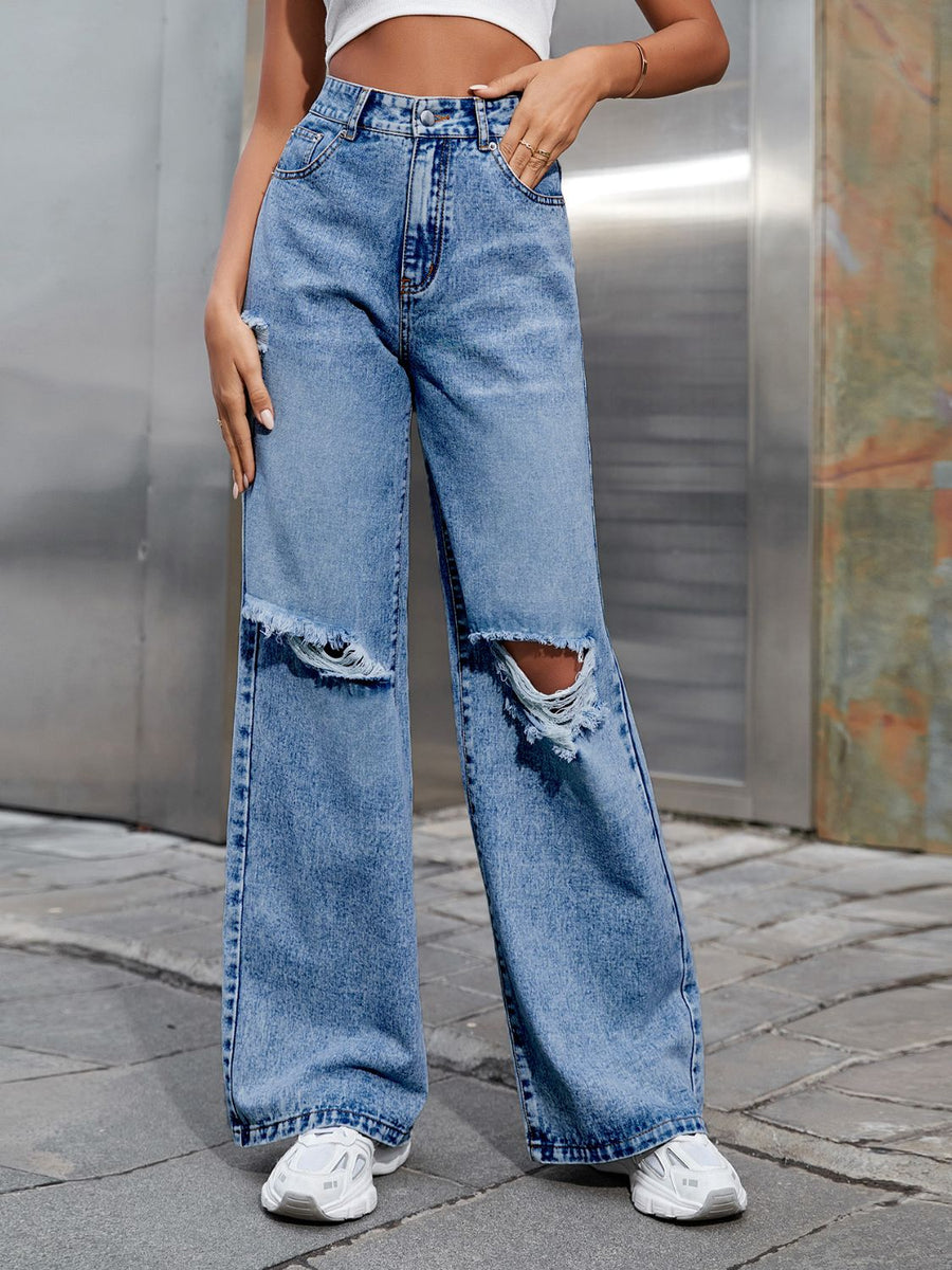 Distressed flare jeans in light wash denim with ripped knees and frayed hem.