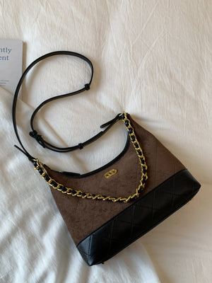 Brown half-moon crossbody bag with chain detail and quilted black trim