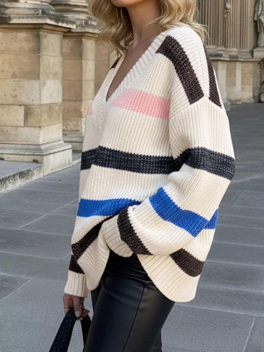 Oversized striped V-neck sweater in cream with black, brown, pink, and blue stripes.