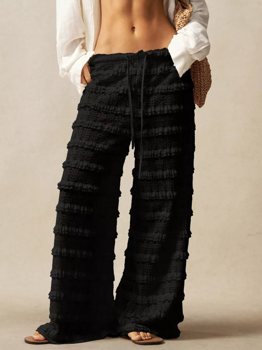 Black wide-leg pants with tiered ruffle detailing and a drawstring waist.