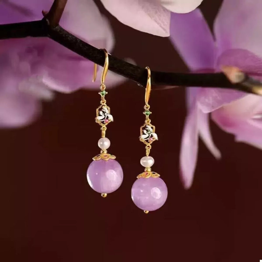 Elegant purple drop earrings with pearl and floral accents.
