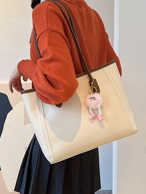 Beige PU leather tote bag with brown trim and a fluffy pink charm.
