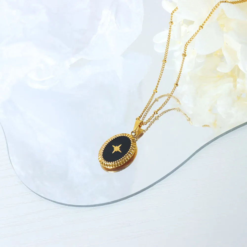 Gold oval pendant necklace with black inlay and starburst detail
