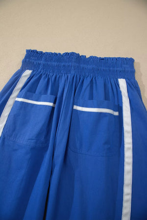 Blue maternity pants with smocked waist, white stripe accents, and patch pockets.