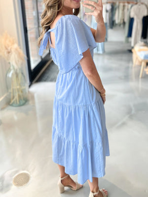 Blue cotton blend midi dress with tiered skirt, flutter sleeves, and tie back detail.