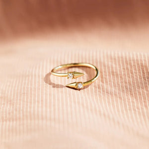 Gold bypass ring with two spiked ends, each set with a clear zirconia stone.