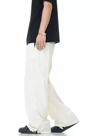 Men's off-white wide-leg sweatpants with a drawstring hem, styled with a black t-shirt.