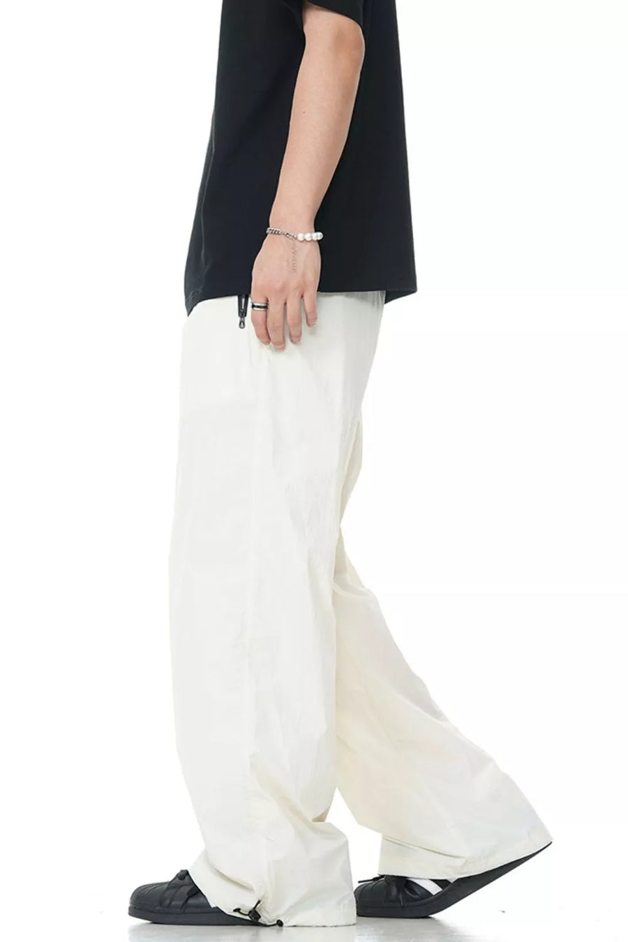 Men's off-white wide-leg sweatpants with a drawstring hem, styled with a black t-shirt.