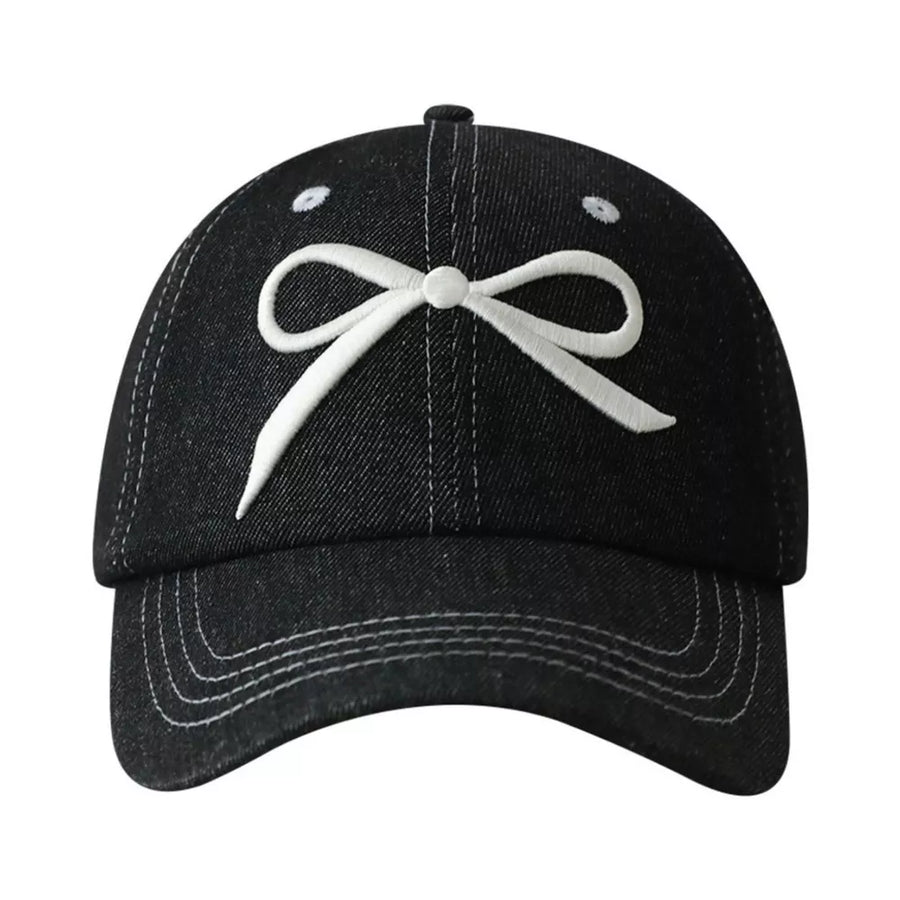 Black baseball cap with white embroidered bow accent and contrast stitching.