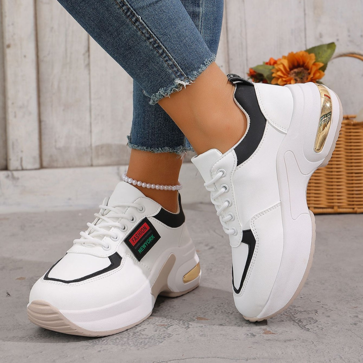 White and black lace-up sneakers with chunky sole and gold heel detail.