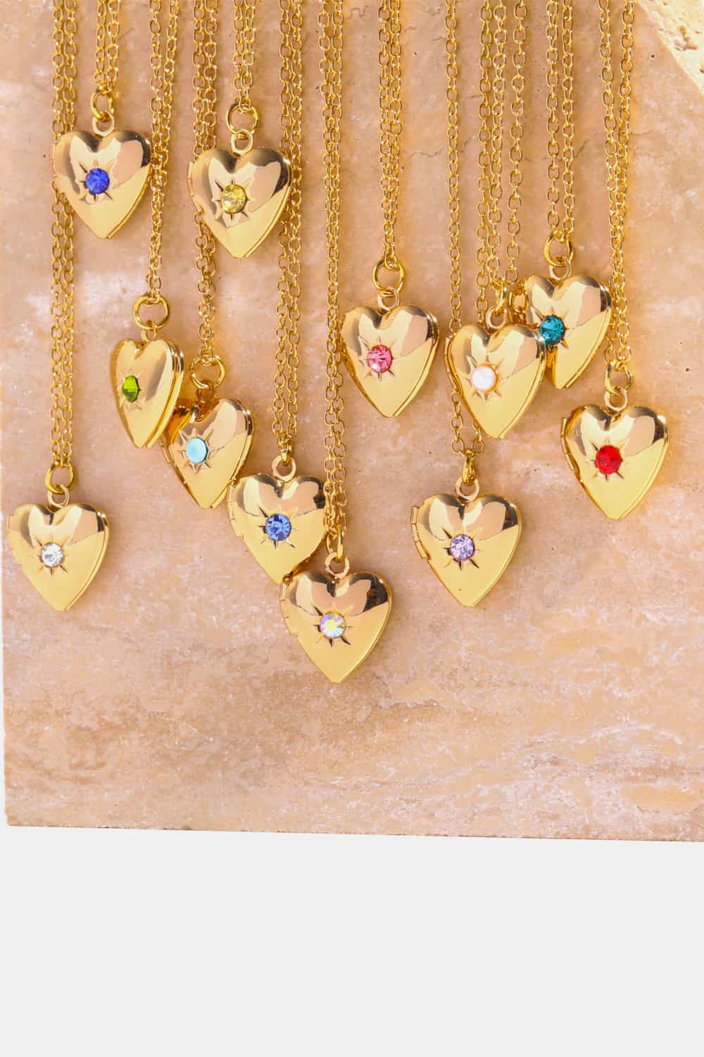 Gold heart locket necklaces with gemstone accents in various colors.