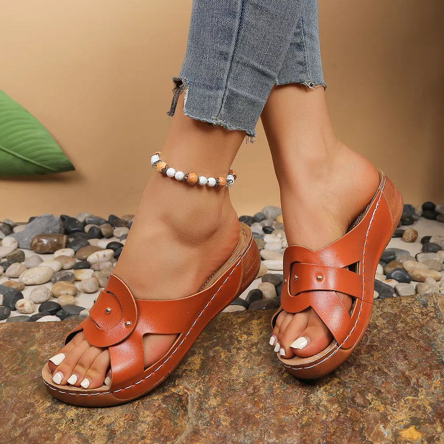 Brown slip-on wedge sandals with riveted detail and broad vamp.