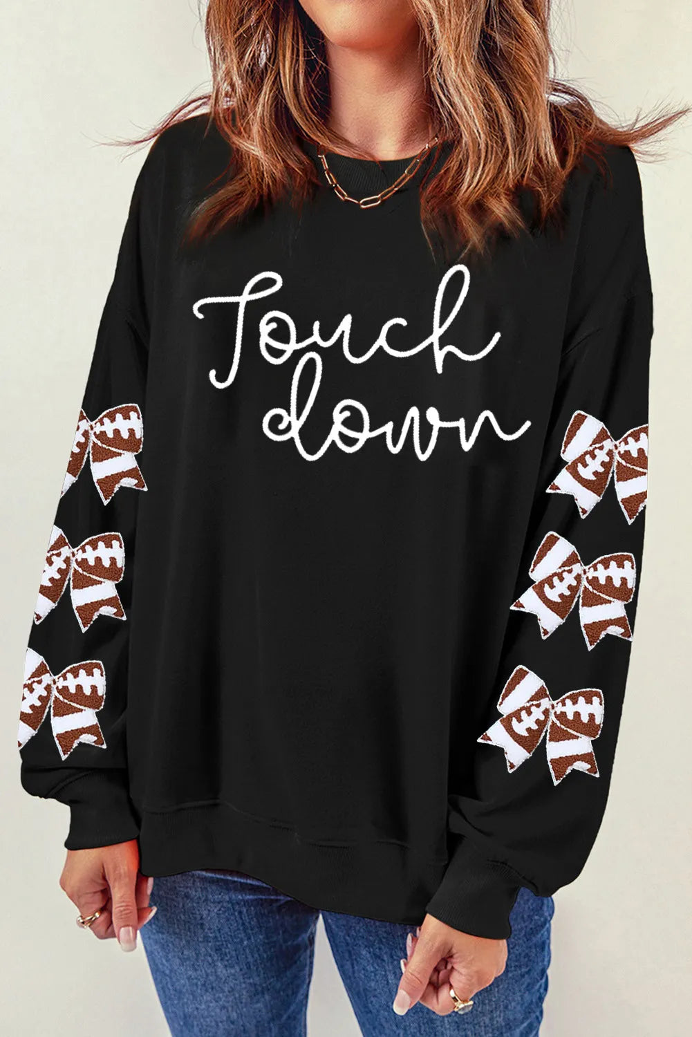 Black sweatshirt with white "Touchdown" graphic and football bow sleeve embellishments