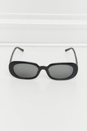Black oval sunglasses with dark lenses and a sleek frame.